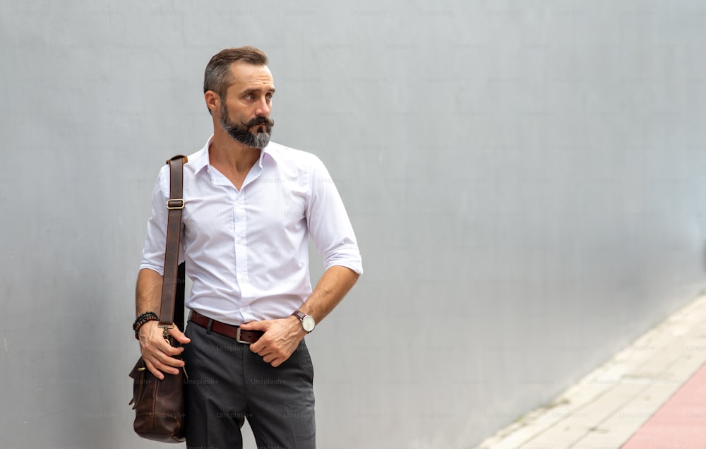 Portrait of Handsome beard guy carrying leather briefcase walking on city street