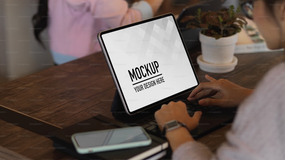 Nahaufnahme der Frau, die mit digitalem Tablet auf einem Holztisch im Café mit Kollegin arbeitet, einschließlich Clipping-Pfad