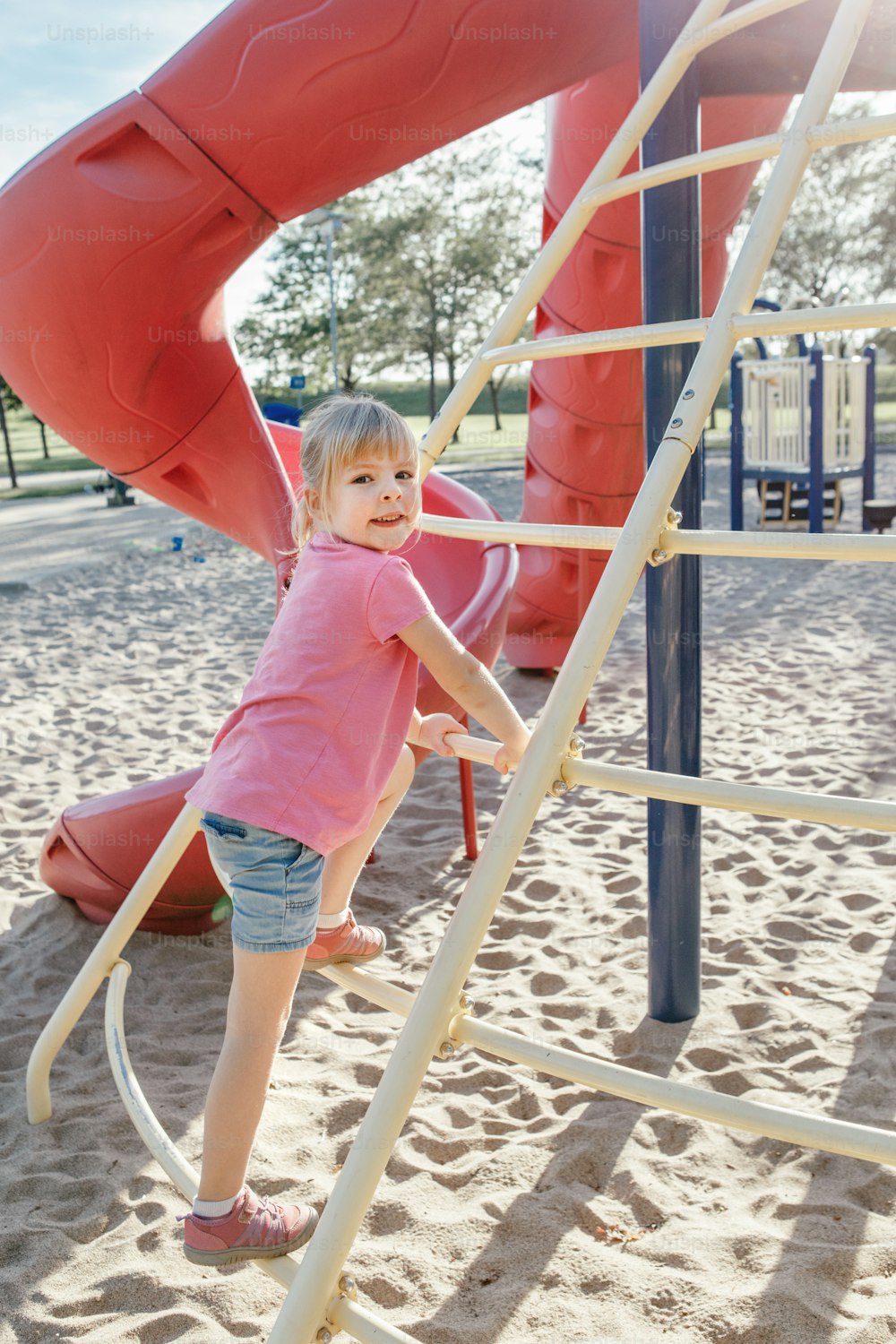 Aktive glückliche tapfere kaukasische Mädchen Treppenkletterer auf dem Spielplatz Schulhof im Freien am sonnigen Sommertag. Saisonale Kinderaktivität draußen. Authentisches Lifestyle-Konzept der Kindheit.