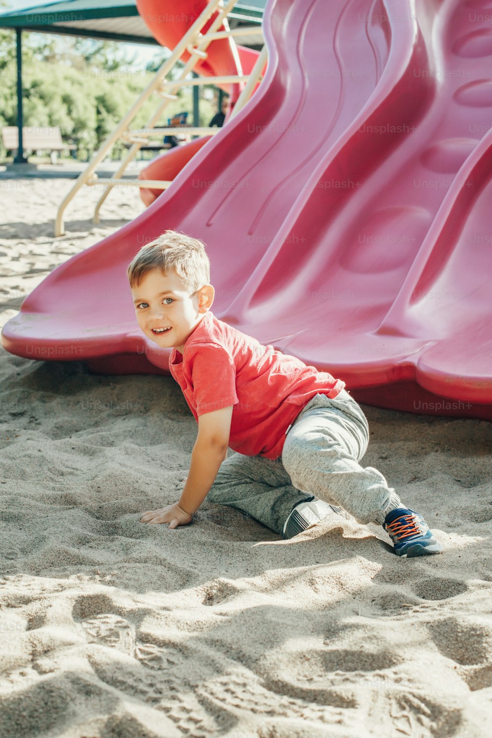 Aktiv glücklich lustig lächelnd kaukasischen Jungen Kind rutscht auf Spielplatz Schulhof im Freien am Sommer sonnigen Tag. Kind hat Spaß. Saisonale Kinderaktivität draußen. Authentisches Lifestyle-Konzept der Kindheit.