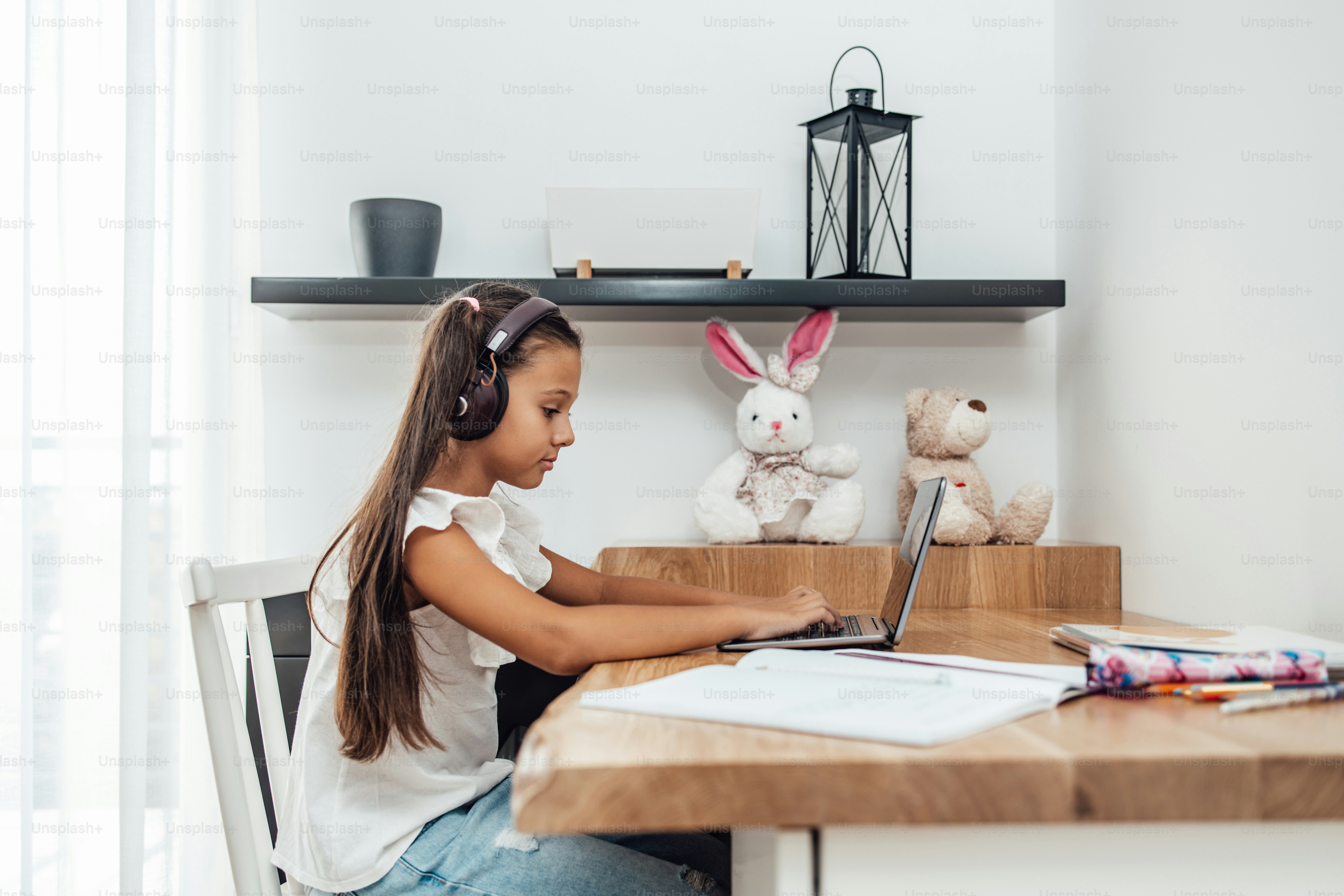 Young little girl having e-learning session during Covid-19 pandemic crisis lockdown or quarantine. Illness prevention and new normal concept.