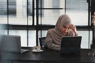 Thoughtful or stressful islamic girl in hijab is feel upset from work in front of tablet computer on desk at office.
