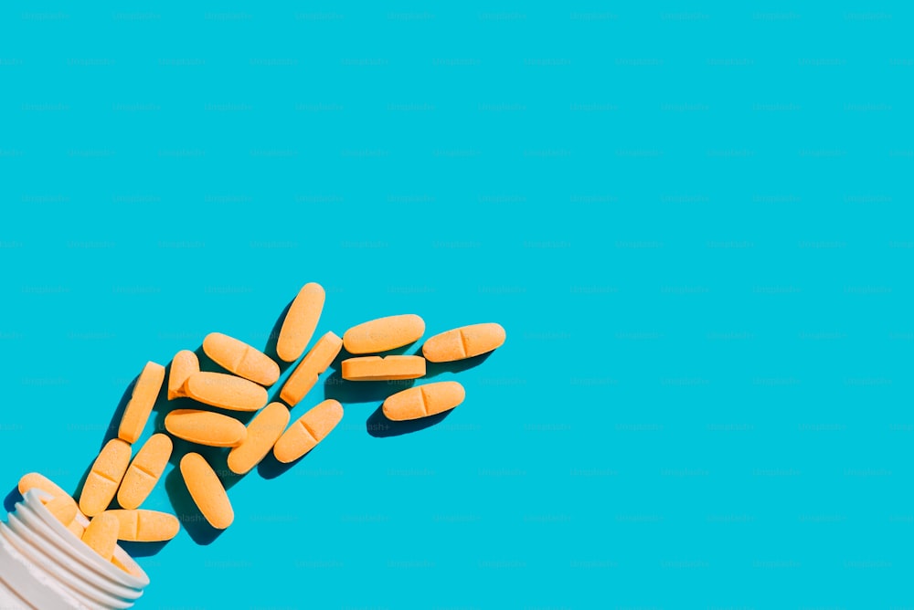 Foto de un diseño minimalista de pastillas y vitaminas sobre fondo azul