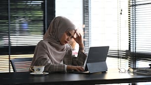 A muslim businesswoman in hijab is  tired from work while sitting in the office.