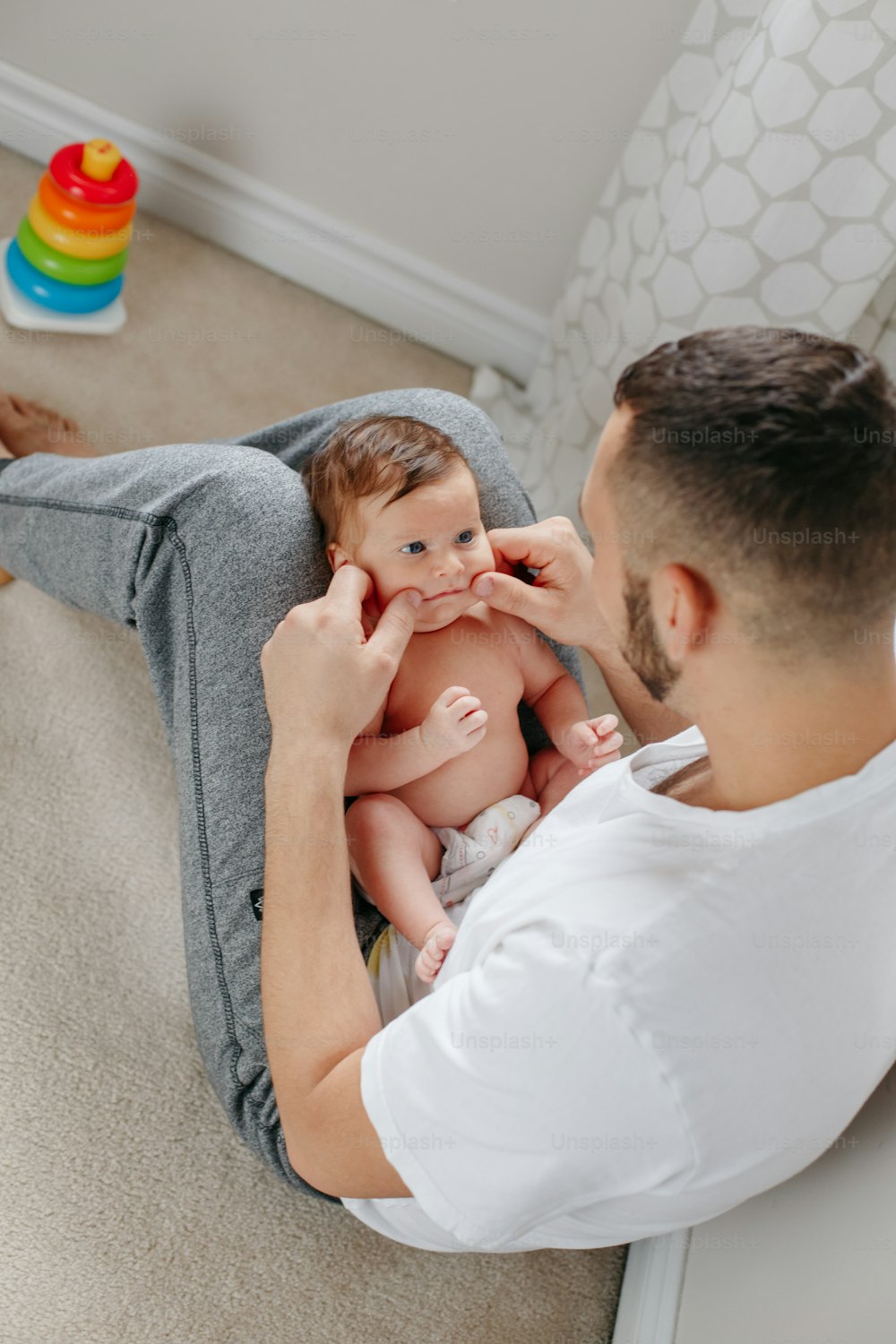 Père caucasien heureux tenant un nouveau-n�é sur les genoux des genoux. Homme, parent, embrassant, berçant, enfant, fille, fils. Moment authentique de vie candide. Fier jeune papa. Fête des pères en famille.