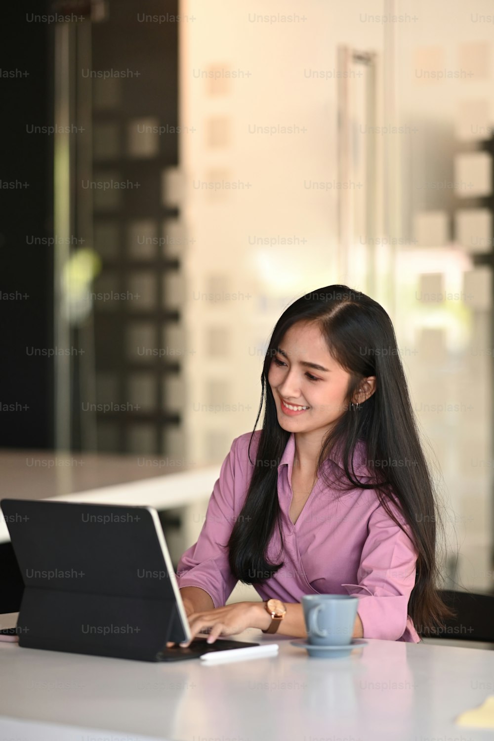 Retrato de una alegre mujer de negocios está sentada detrás de su computadora portátil y trabajando en la oficina.