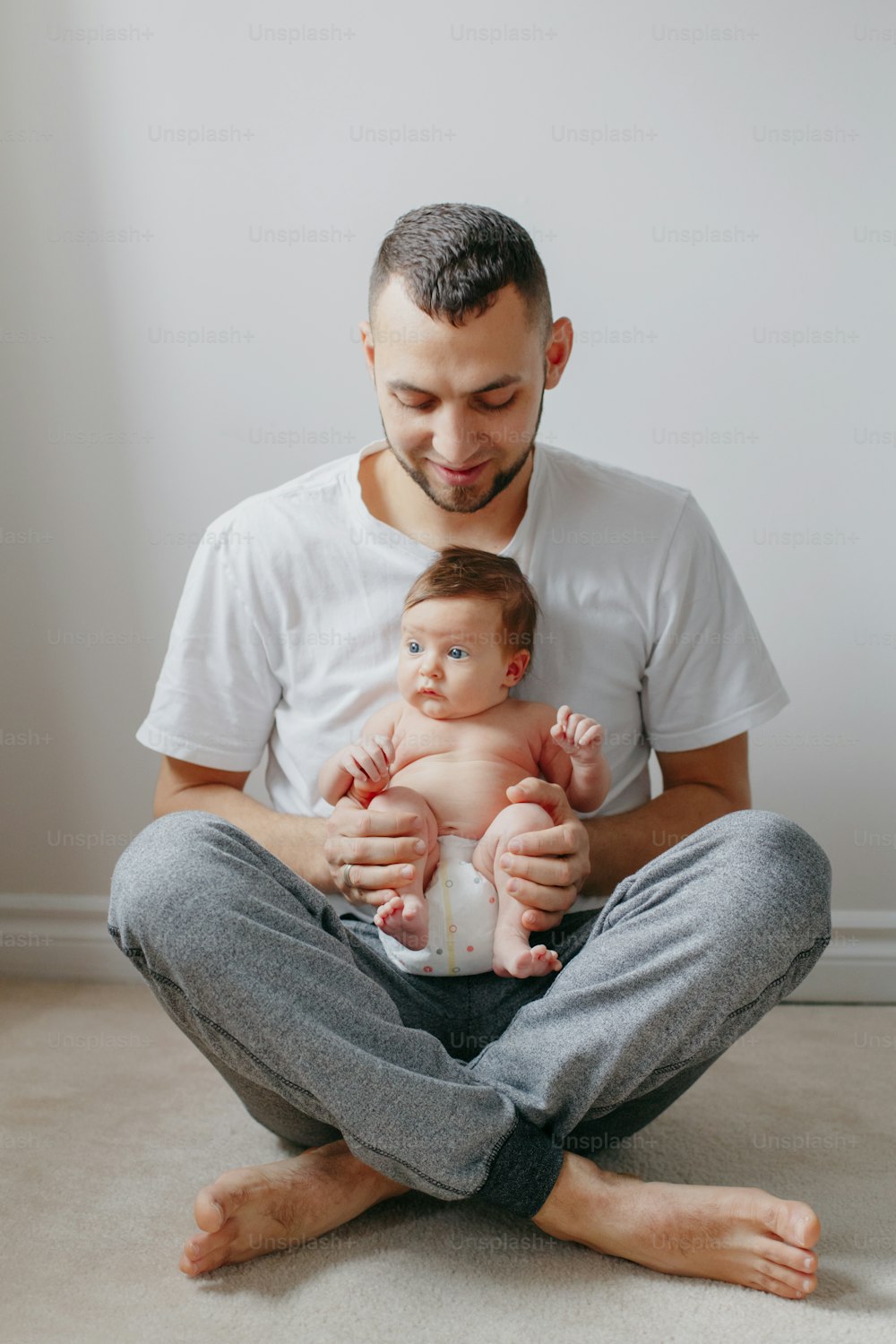 Happy Caucasian father holding newborn baby on laps knees. Man parent embracing rocking child daughter son. Authentic lifestyle candid moment. Proud young dad. Family fathers day.