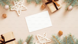 Maquette de carte de voeux de Noël sur fond beige pastel avec des boîtes cadeaux, des étoiles, des boules, des décorations, des branches de sapin. Pose à plat, vue de dessus. Style minimaliste.