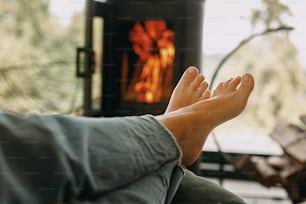 Woman barefoot relaxing in comfortable home, cozy warm moments. Feet on background of modern black fireplace and big windows with view on mountains.
