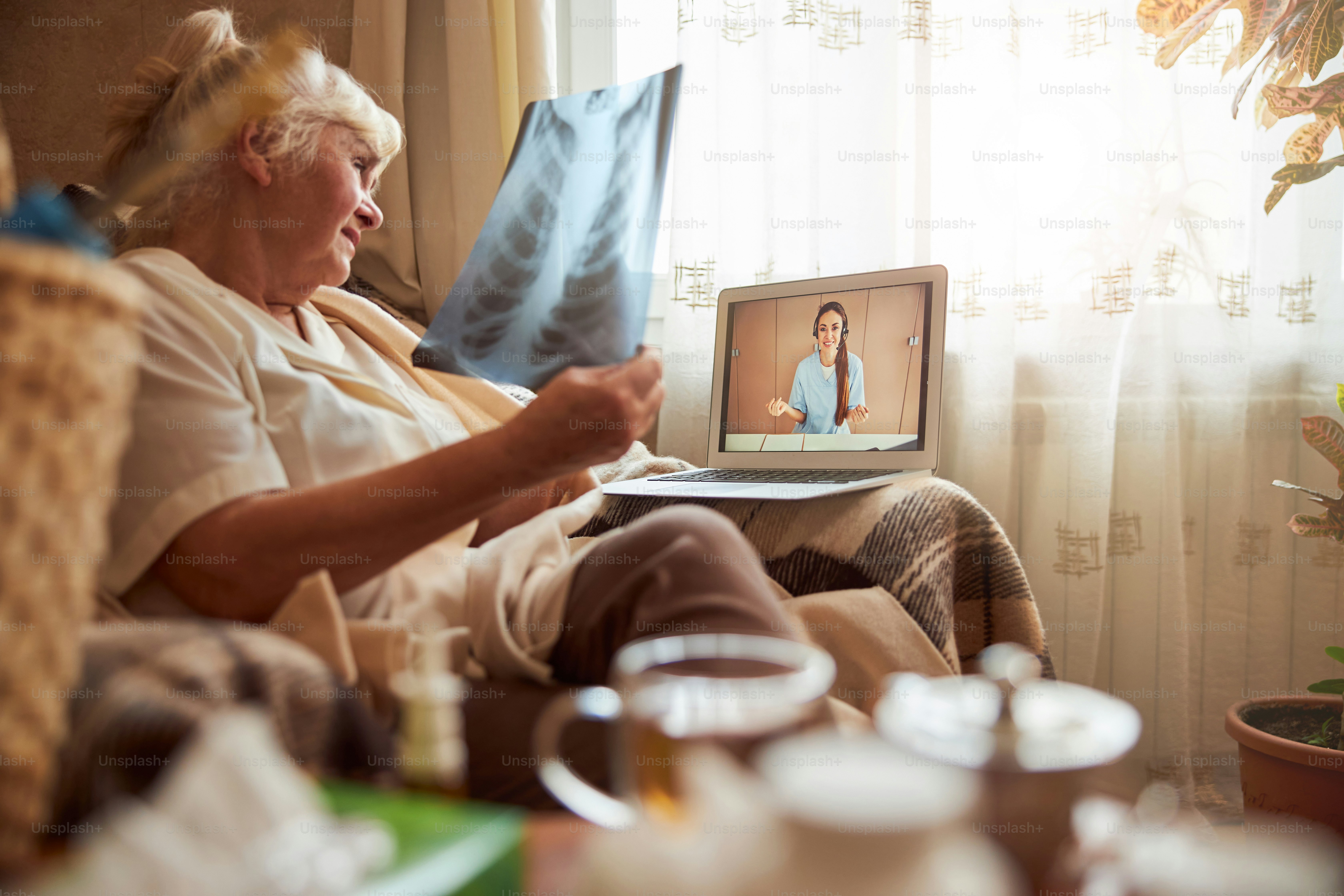 Elderly lady sitting in armchair and holding chest xray while talking