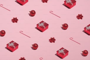 Motif de Noël composé de boîtes cadeaux rouges, de cannes de bonbon, de boules, de décorations sur fond rose. Noël, Nouvel An, concept de vacances d’hiver.