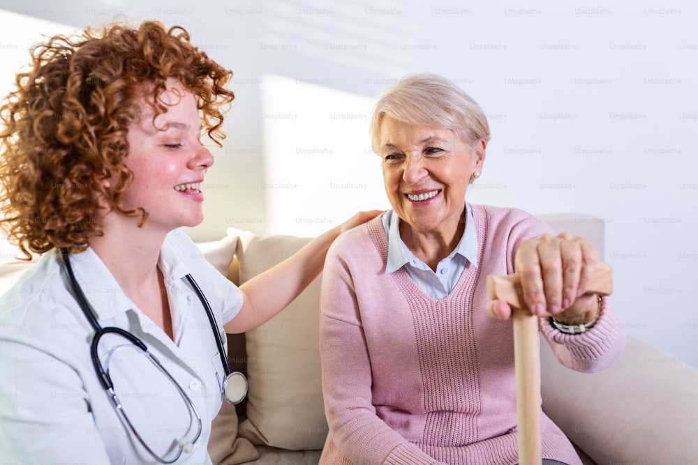 Enge positive Beziehung zwischen älterem Patienten und Pflegepersonal. Glückliche ältere Frau, die mit einer freundlichen Pflegekraft spricht. Junge hübsche Pflegerin und ältere glückliche Frau