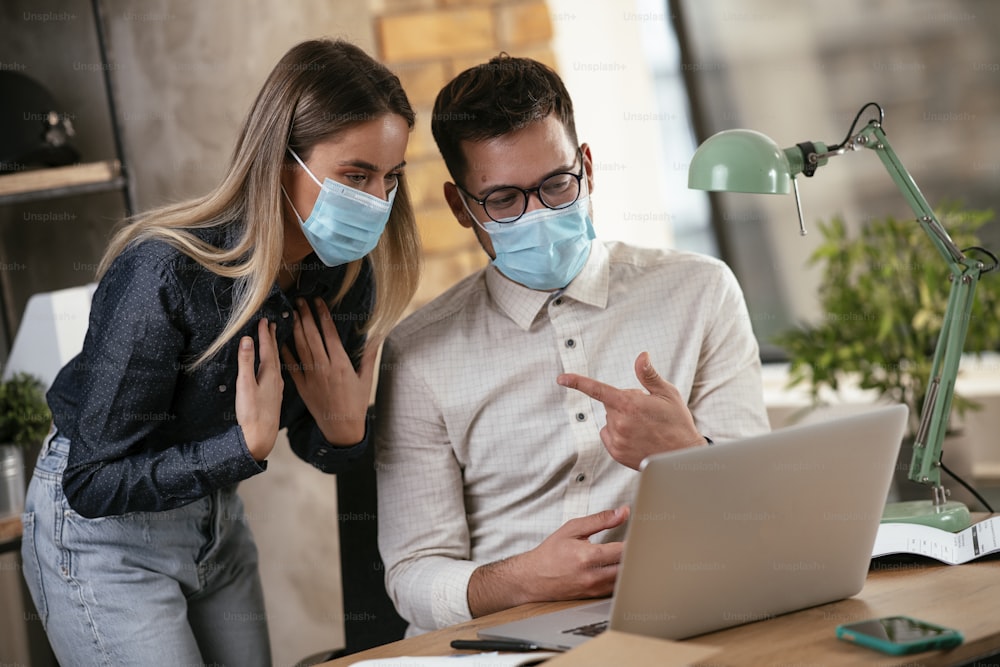 Businessman and businesswoman with medical mask in office. Colleagues working together. COVID - 19 virus protection