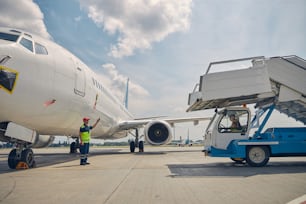 Caucasian aircraft maintenance supervisor in uniform standing in front of a passenger boarding stairs truck