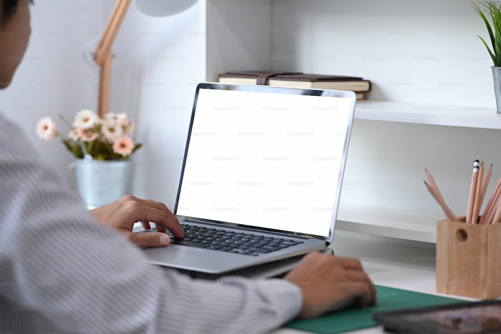 Um designer criativo está trabalhando em laptop com tela em branco no escritório.