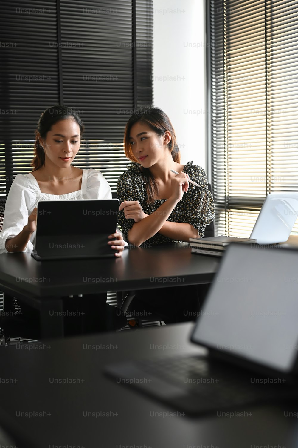 Two businesswomen are using computer tablet and discussing new project at office.