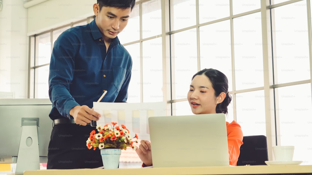 Two business people talk project strategy at office meeting room. Businessman discuss project planning with colleague at modern workplace while having conversation and advice on financial data report.