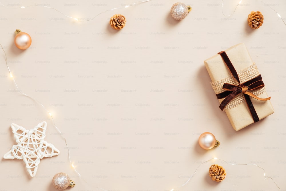 우아한 크리스마스 구성입니다. 선물 상자, 별, 공 장식, 파스텔 베이지색 배경에 화환으로 만든 크리스마스 프레임. 미니멀한 북유럽 스타일. 플랫 레이.