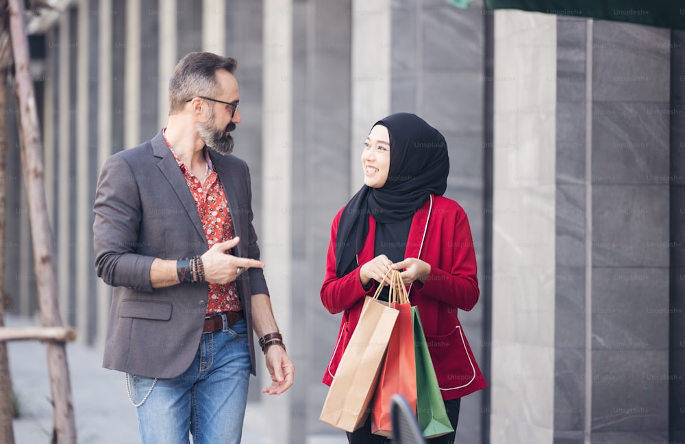 행복 한 무슬림 여자와 소년 친구가 종이 가방을 들고 도시 쇼핑 손을 들고