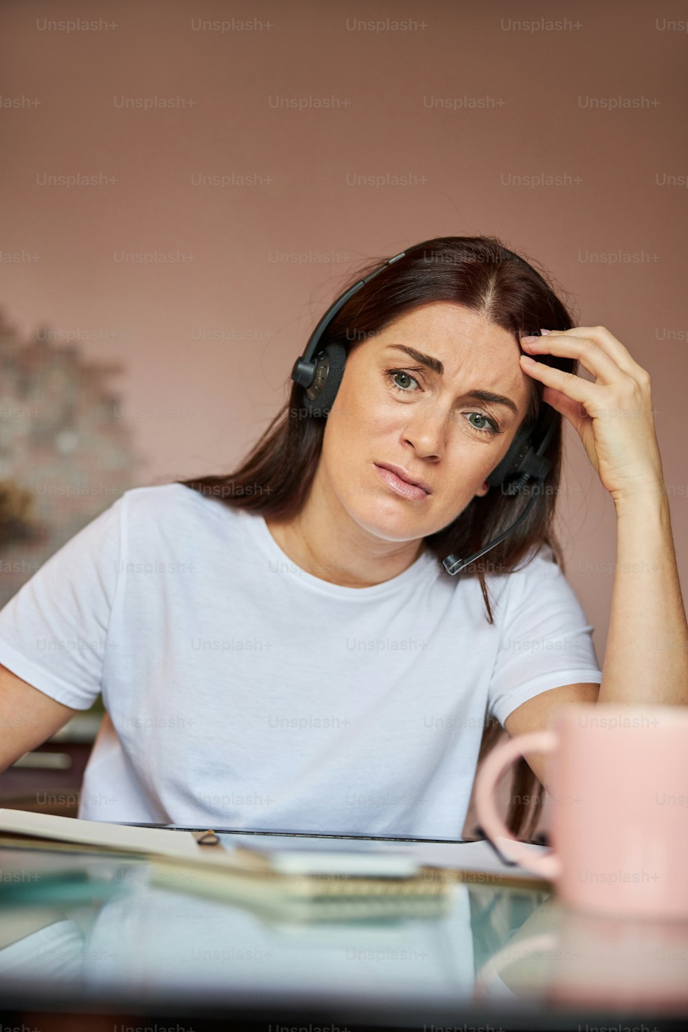 Woman working remotely in a headset with an arm on her head not wanting to do her job