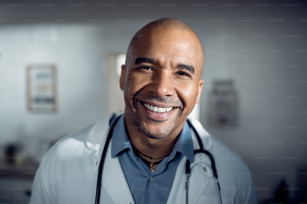 Nahaufnahme des glücklichen schwarzen Arztes, der in einer medizinischen Klinik arbeitet und in die Kamera schaut.