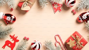 Décorations de Noël rouges et coffrets cadeaux avec des branches de sapin sur fond beige. Bordure de cadre de Noël, modèle de carte de voeux saisonnier. Mise à plat, vue de dessus, espace de copie.