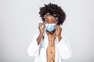 Portrait of young beautiful black female EMS medical worker, wearing uniform and protective face mask, studio headshot isolated on white background, stress and worry due to Coronavirus COVID-19 pandemic