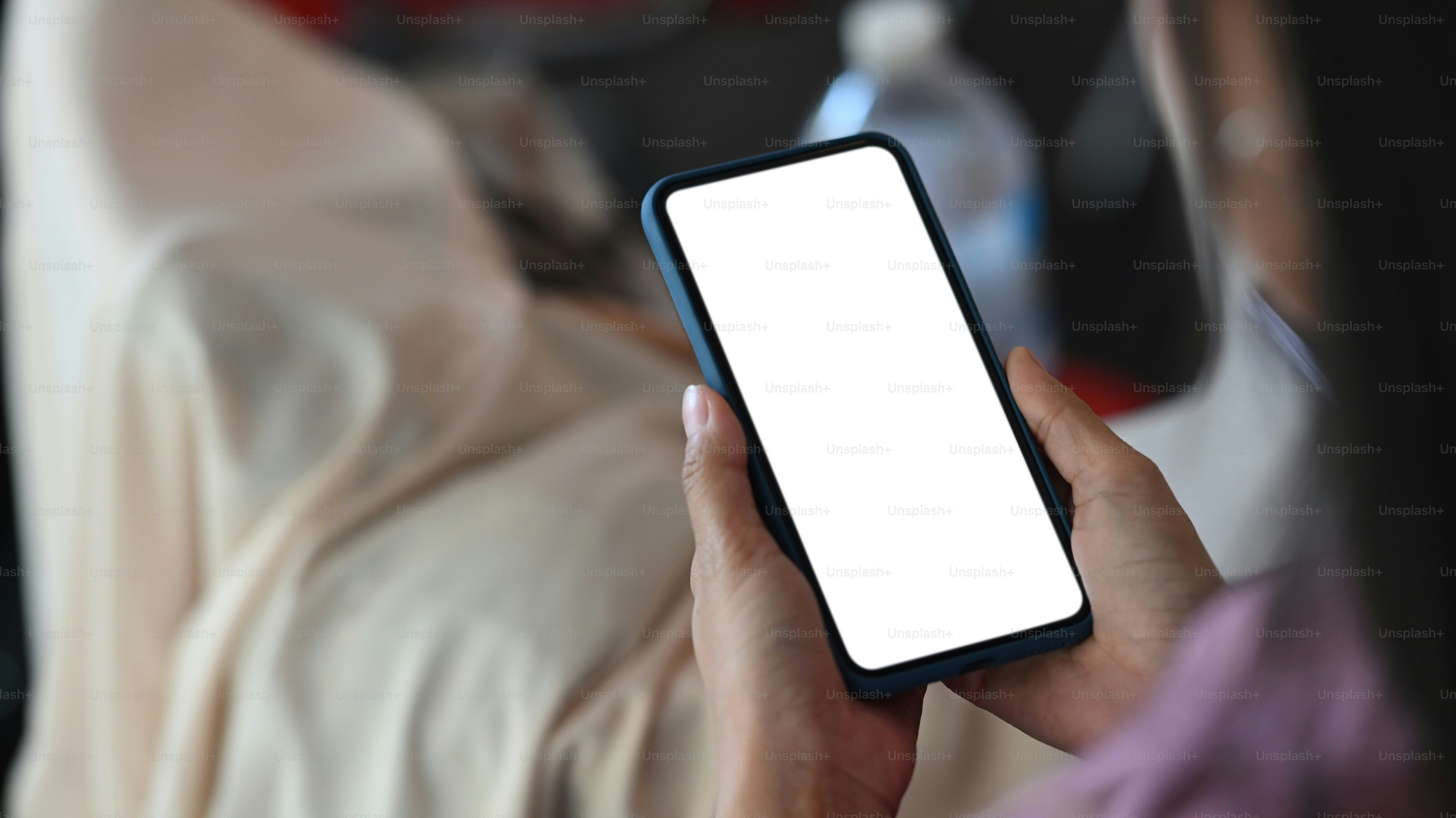 Vista de cerca de la mujer usando un teléfono inteligente con pantalla blanca en la sala de oficinas. Pantalla en blanco para montaje gráfico.