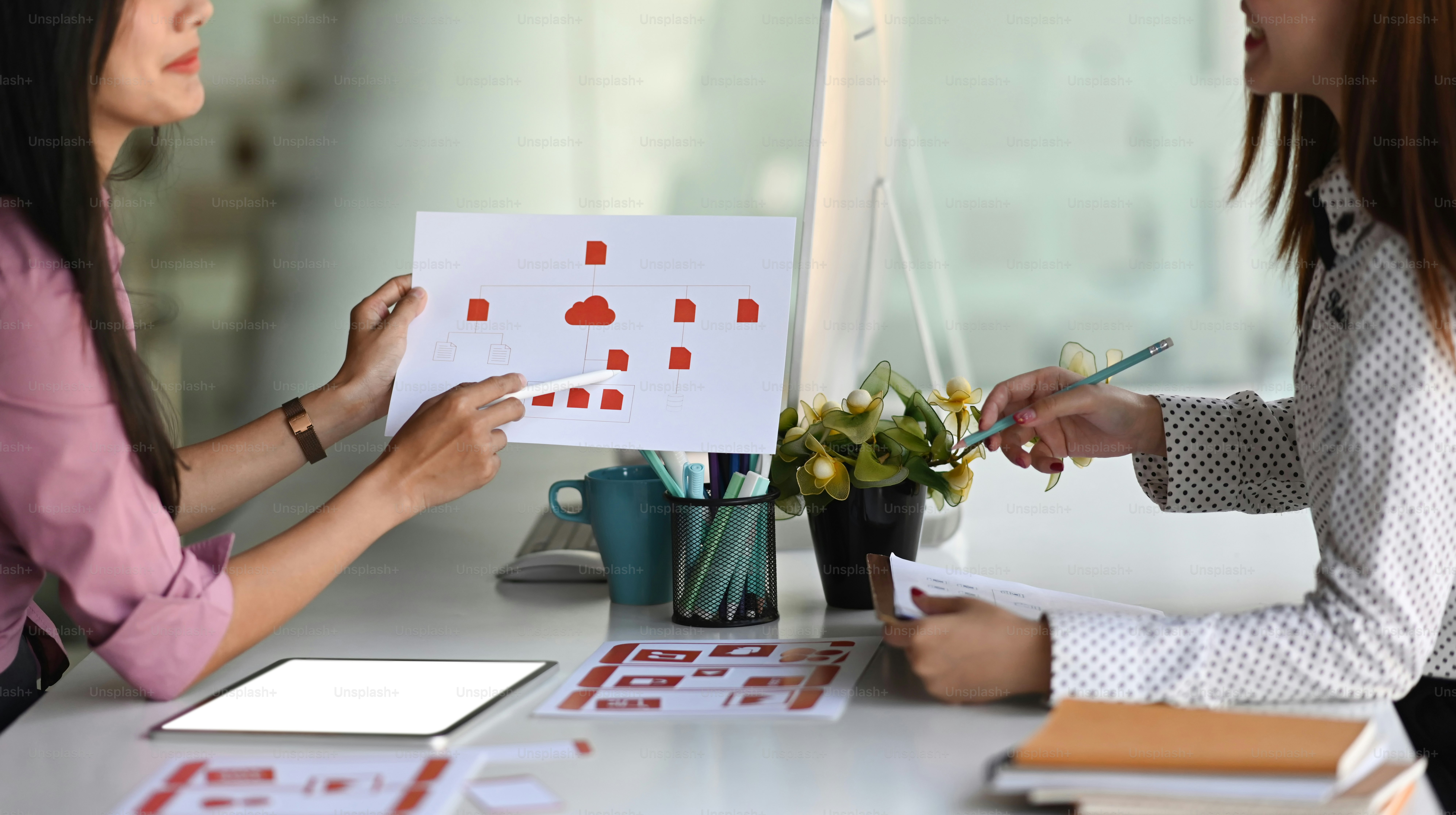 Cropped shot of Asian ux developer and ui designer are discussing mobile app interface design in meeting at modern office.