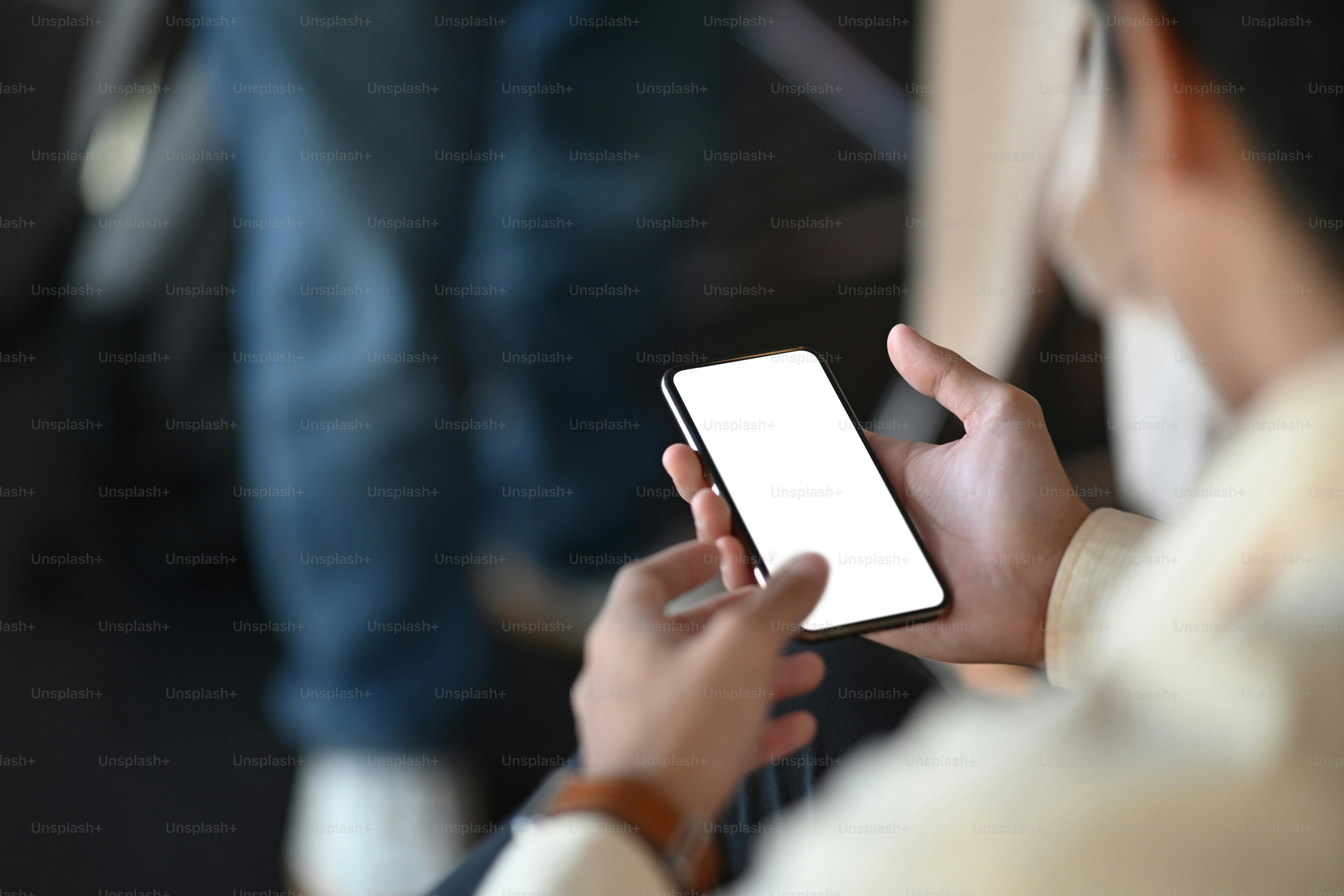 Toma recortada de manos de hombre usando un teléfono móvil mientras está sentado en la sala de oficinas.