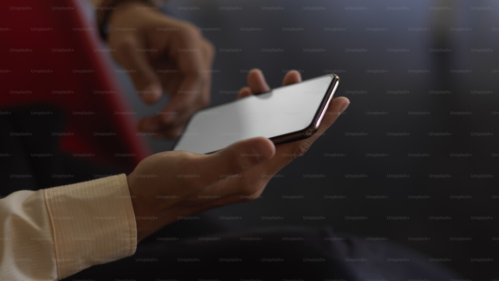 Side view of hand holding mock up smartphone in dark background