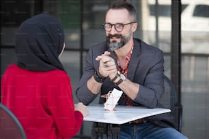 Asian Muslim businesswoman in coffee shop talking to customer or boy friend