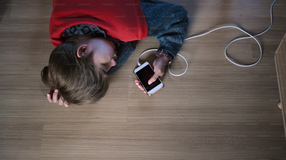 A young girl addicted to mobile phone is sleeping on the floor in living room.