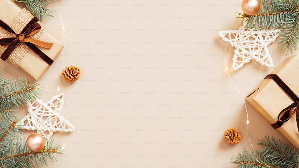 Cornice natalizia. Confezioni regalo, stelle, rami di pino e pigne su sfondo beige pastello. Modello di biglietto d'auguri di Natale, modello di cartolina di Capodanno. Posa piatta, vista dall'alto, spazio di copia.