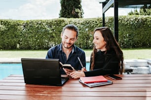 young mexican woman working on laptop while latin man sitting near her in the rest area of the office outdoors in Latin America