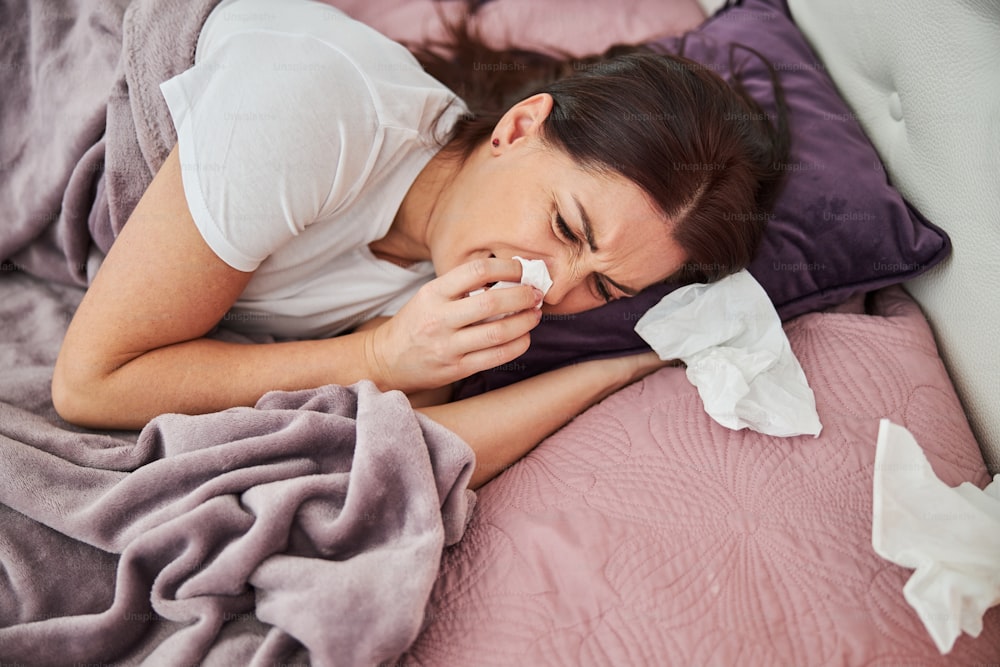 病気でひどい気分になり、鼻水を止めるためにナプキンを鼻に持ってきた女性