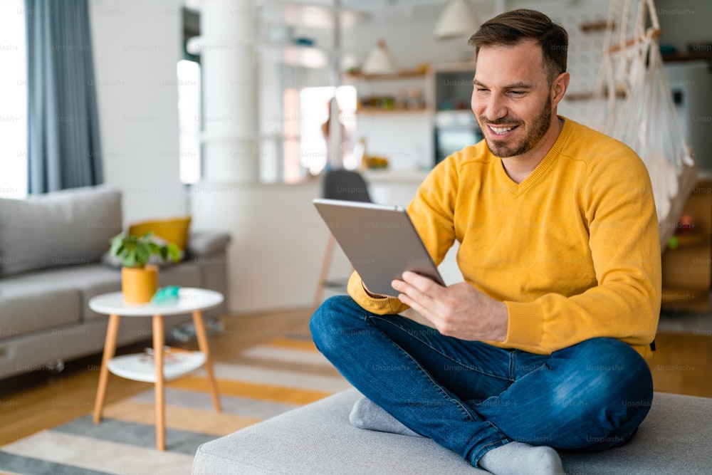 Happy man relaxing on sofa with digital tablet at home