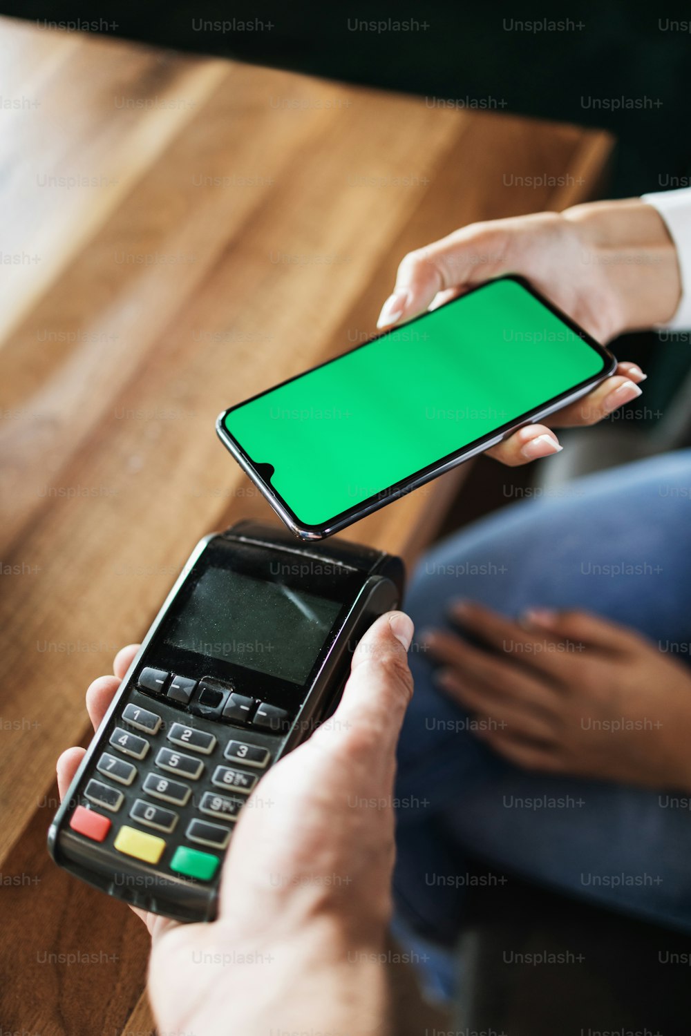 Customer making payment in modern cafe or restaurant by smartphone using NFC (near field communication) wireless technology. Close up shot. Consumer technology concept.