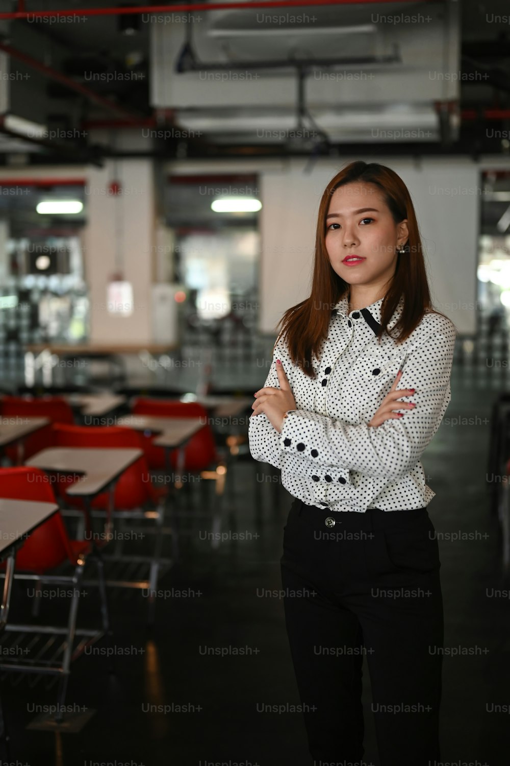 Portrait of confident business woman is standing in meeting room with her arms crossed.