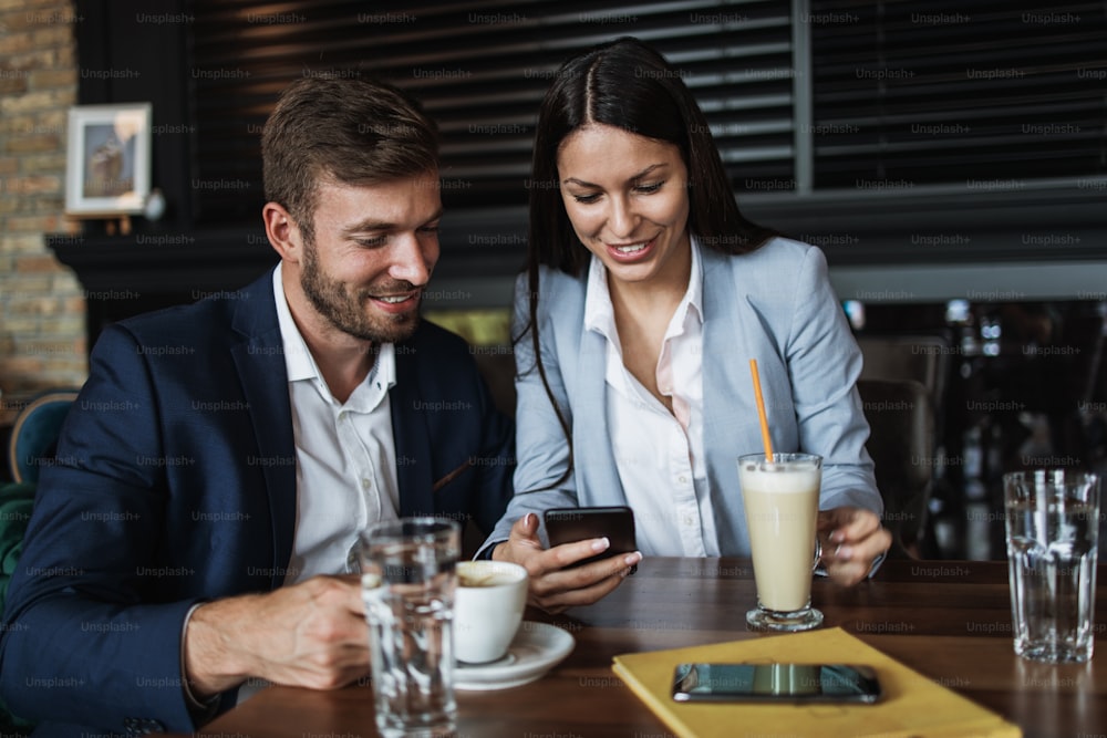 Happy couple man and woman sitting in modern cafe bar or restaurant and drinking coffee.