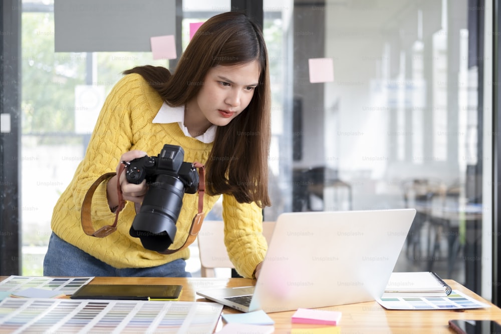 Young photographer checking images from digital camera in her computer laptop.