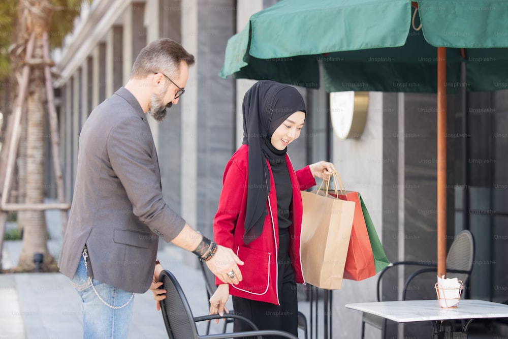 Mulher muçulmana feliz e namorado com a mão de compras da cidade segurando sacos de papel