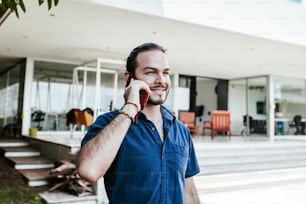 Jovem empresário latino andando e falando ao telefone celular ao ar livre no México