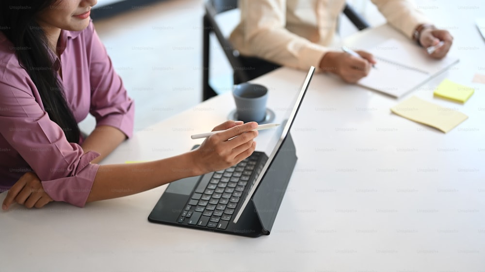 Two business partners are discussing financial report with computer tablet in meeting room.