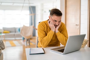 Frustrated young business man working on laptop at home