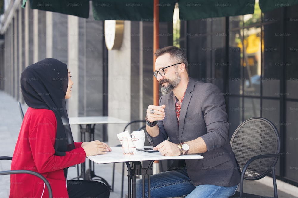 Empresária muçulmana asiática no café conversando com cliente ou namorado