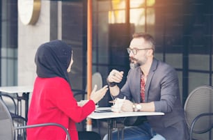 Asian Muslim businesswoman in coffee shop talking to customer or boy friend