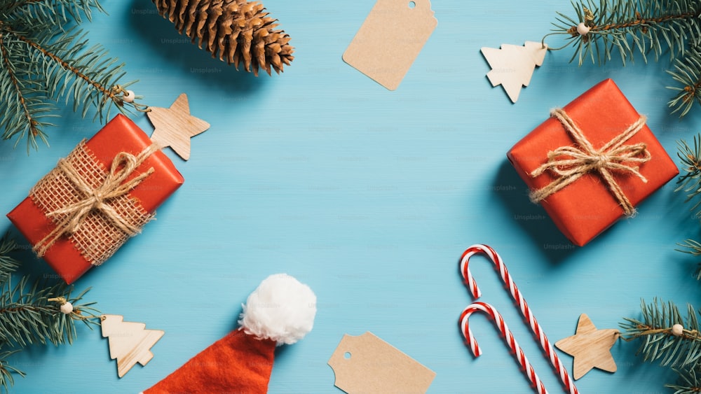 빈티지 크리스마스 플랫 레이 구성. 크리스마스 나무 가지, 선물 상자, 산타 모자, 사탕 지팡이, 파란 테이블에 나무 크리스마스 장식. 복사 공간이 있는 상위 보기입니다. 복고풍 스타일.