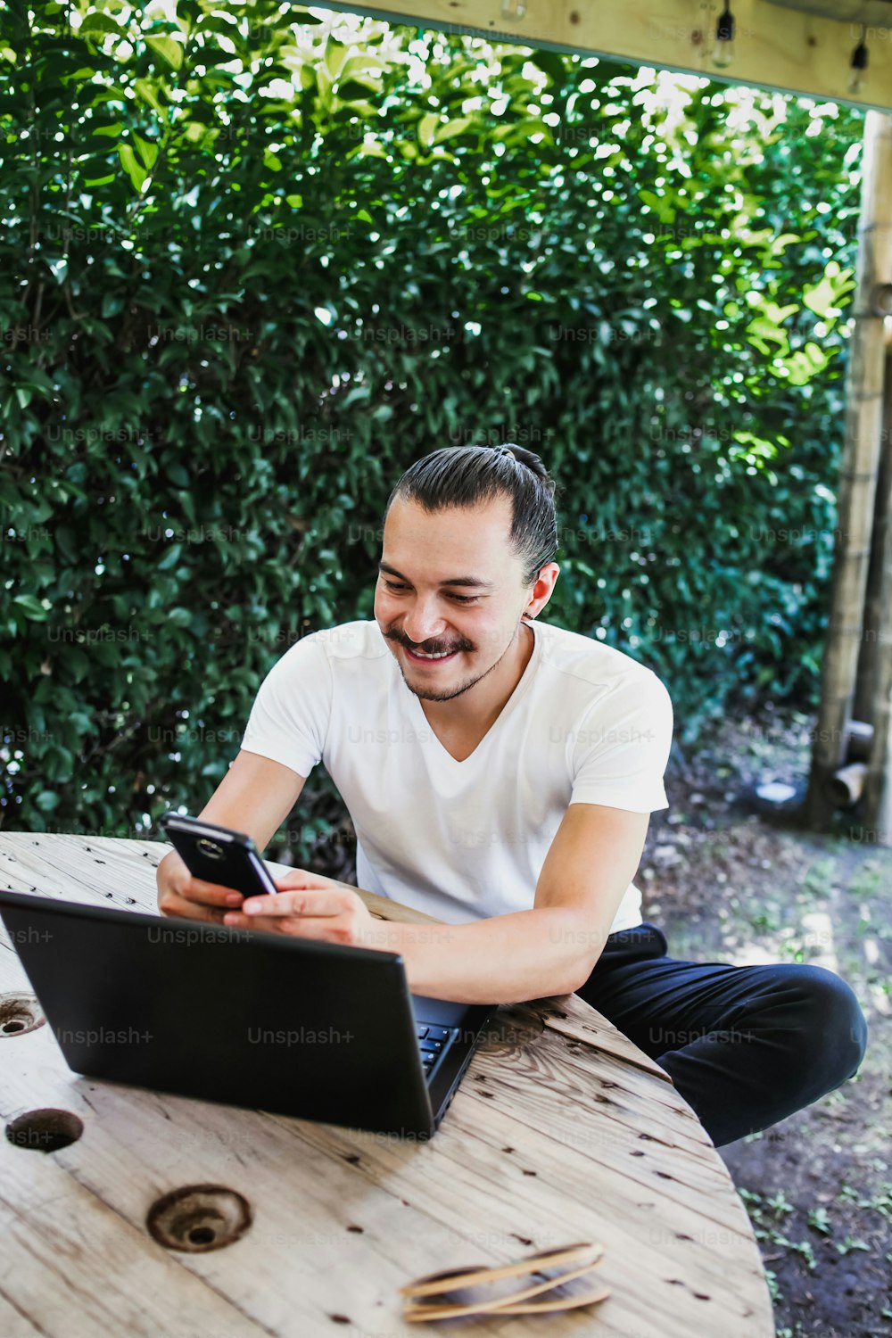 Homme mexicain utilisant un smartphone et un ordinateur sur la terrasse d’une maison à Mexico
