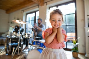 Porträt eines glücklichen kleinen Mädchens drinnen zu Hause, in die Kamera schauend.